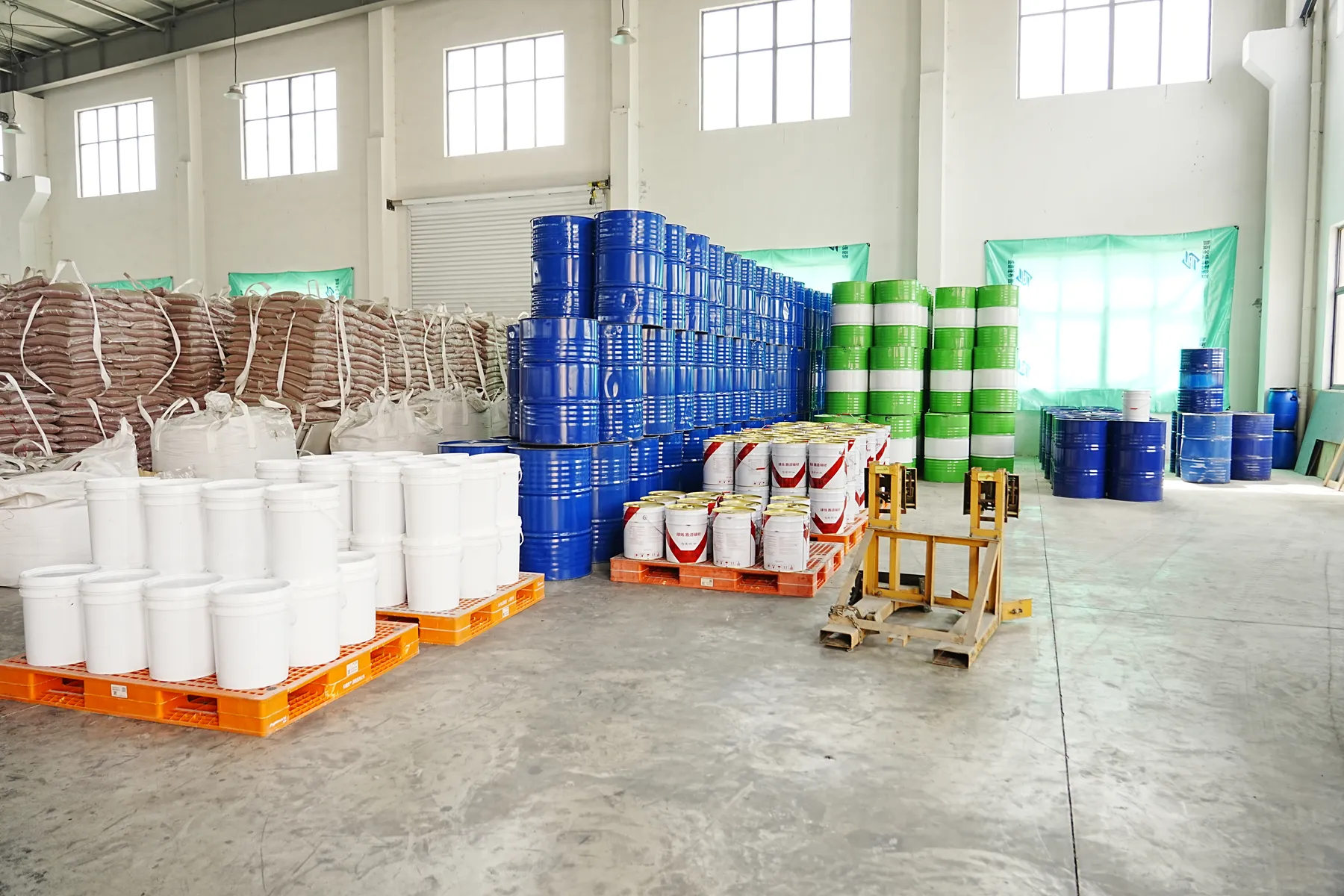 Drums, buckets and bagged materials arranged in a warehouse area